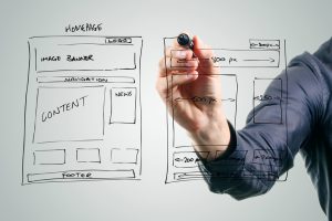 designer drawing website development wireframe with black marker